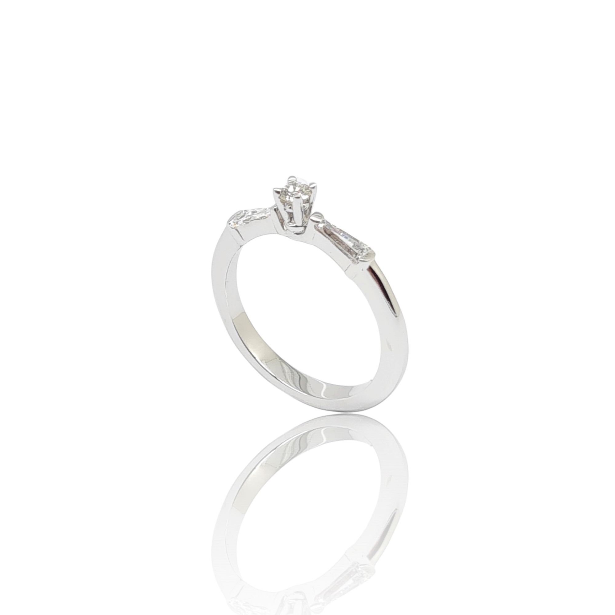 Μονόπετρο δαχτυλίδι απο λευκόχρυσο κ18 με στρογγυλό σκελετό με κεντικό διαμάντι σε καστόνι και δύο διαμάντια σε σχήμα τραπέζιου (code P2021)